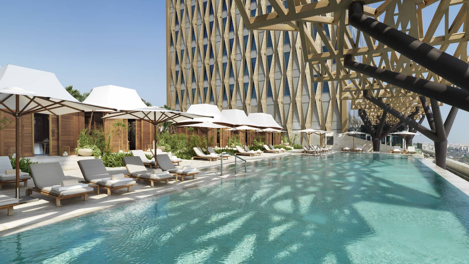 An olympic size pool surrounded by lounge chairs shaded by large white umbrellas