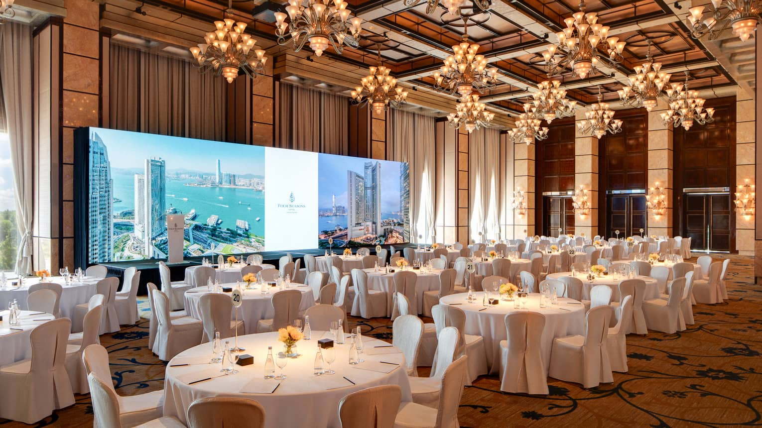 Large hotel ballroom with banquet seating an wide screen in the front of the room