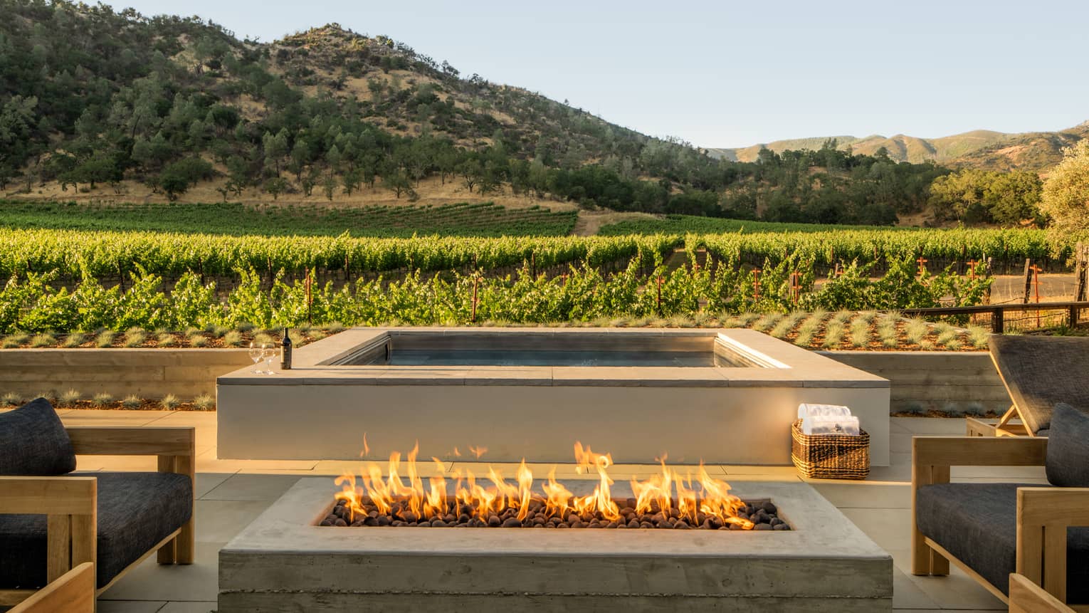 An outdoor terrace featuring a gas fireplace and pool, overlooking vineyards
