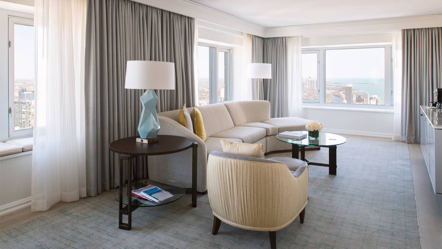 Hotel suite seating area with bright windows, white sofa and armchair