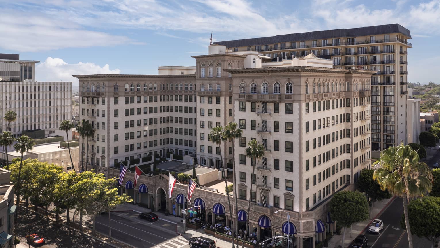 The exterior of a large stone building surrounded by streets and palm trees.