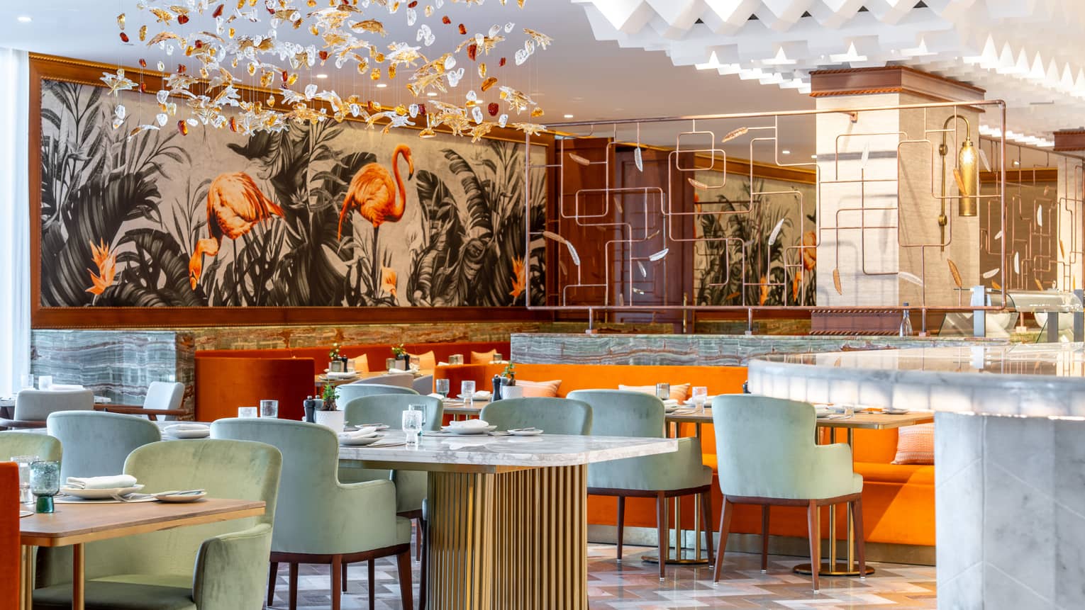 Indoor restaurant with orange and turquoise seating, flamingo mural and abstract hanging installation