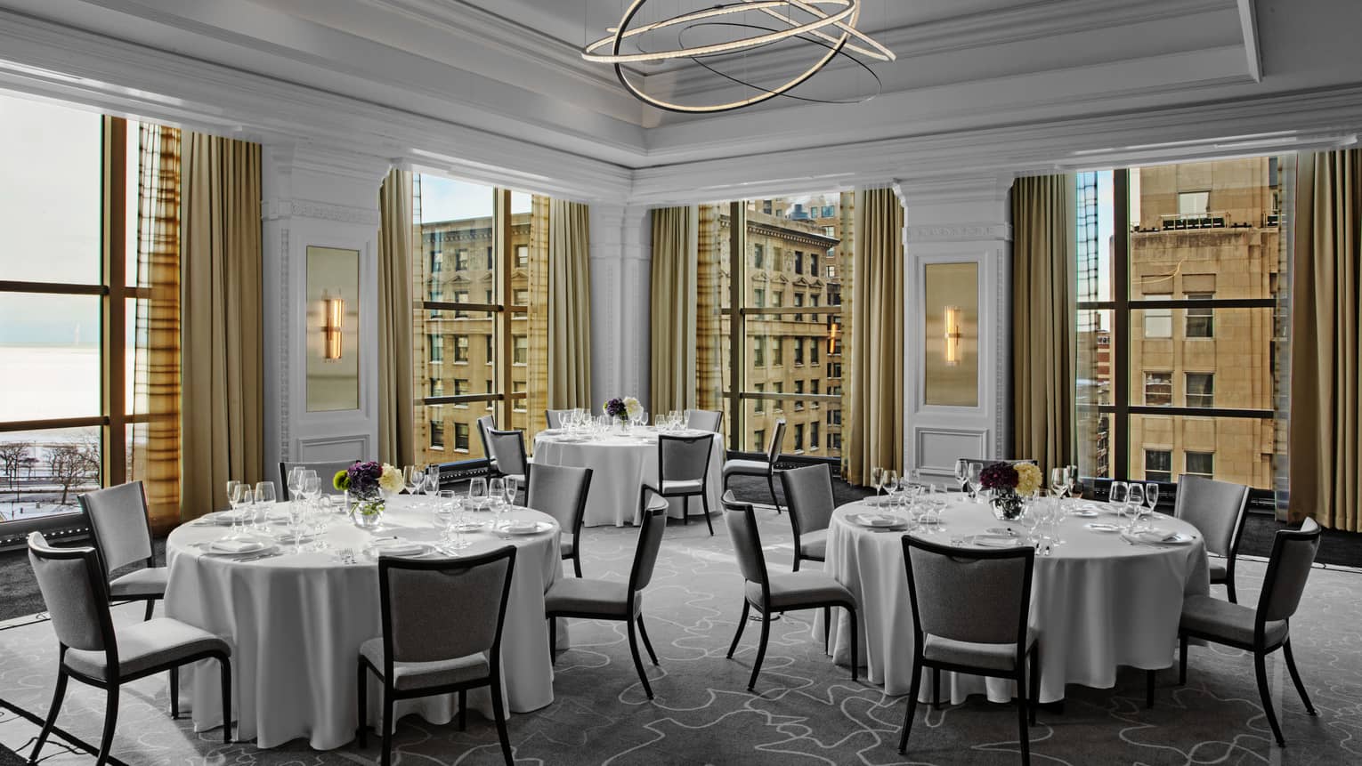 A room with round tables, large windows and dim lighting.