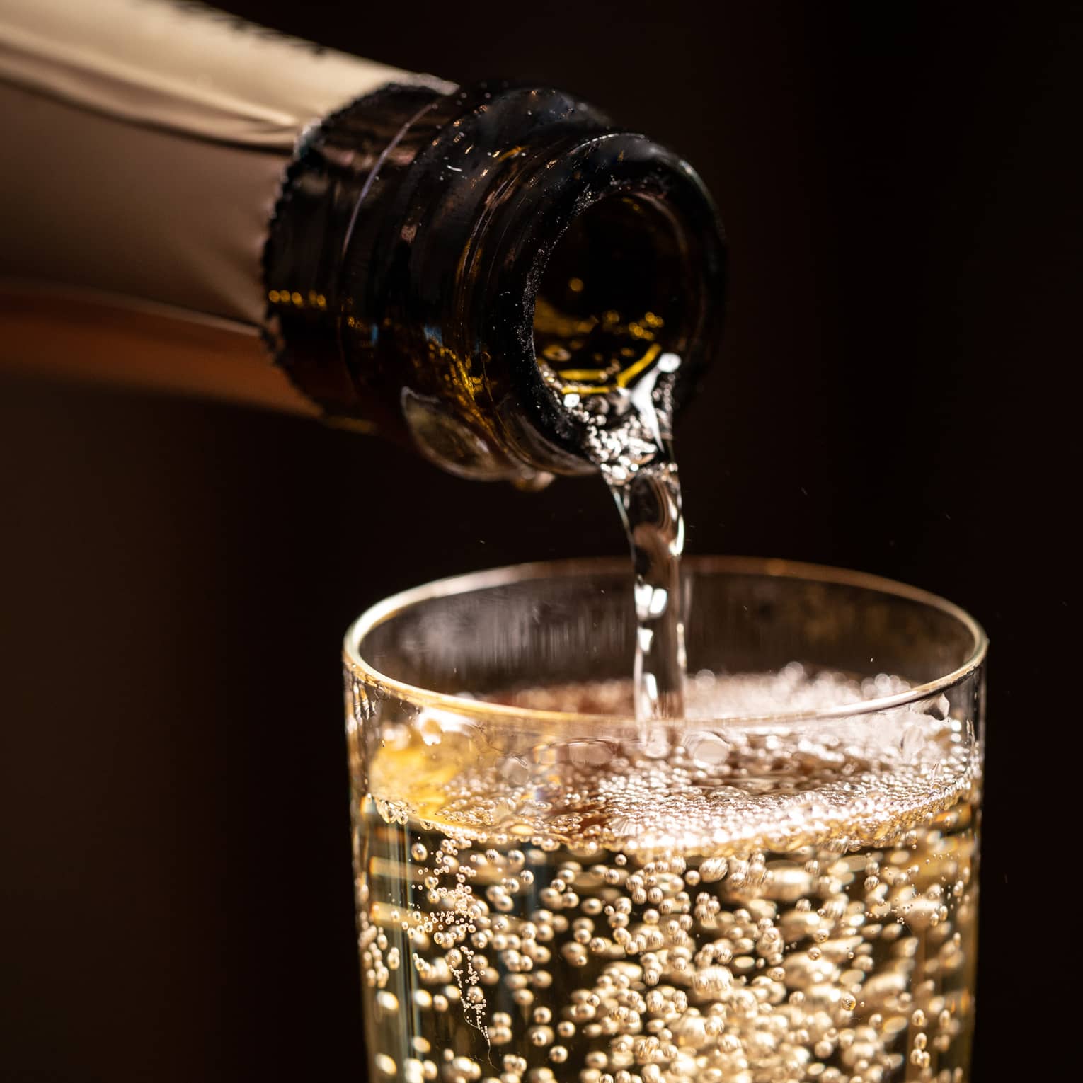 A bottle of wine being poured into a glass.