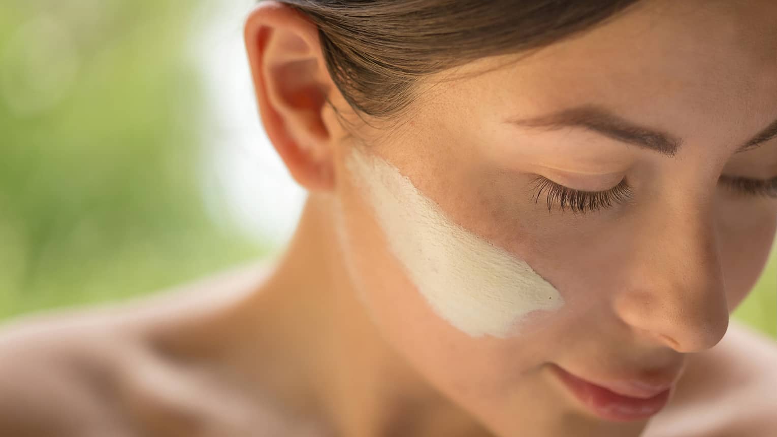 Close-up of side of woman's face with lotion on cheek