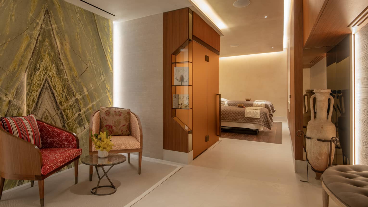 Spa seating vignette against marble wall leading to couples? treatment room with two spa tables