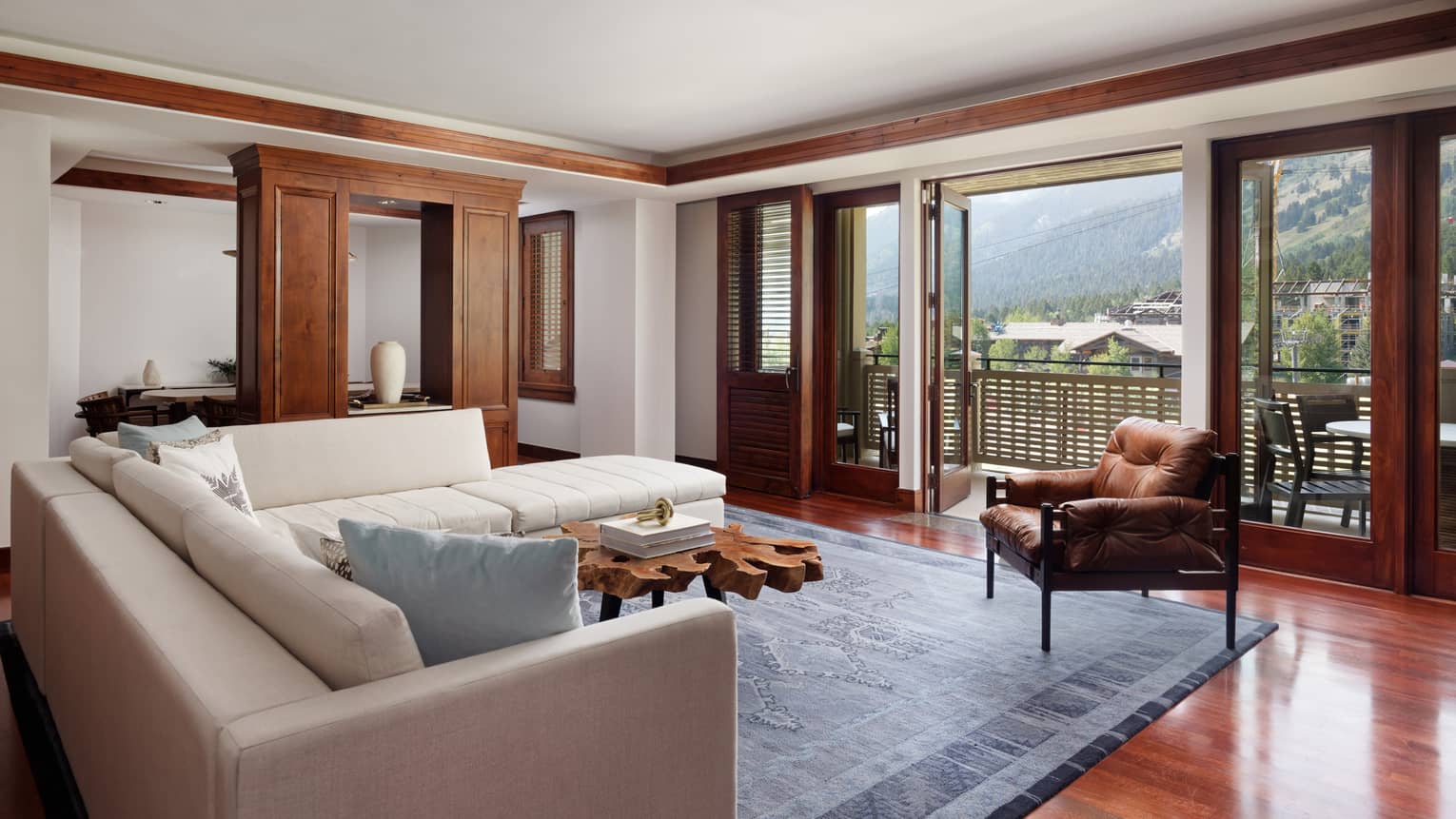 Living room with cream L-shaped sofa, leather arm chair and views of mountains