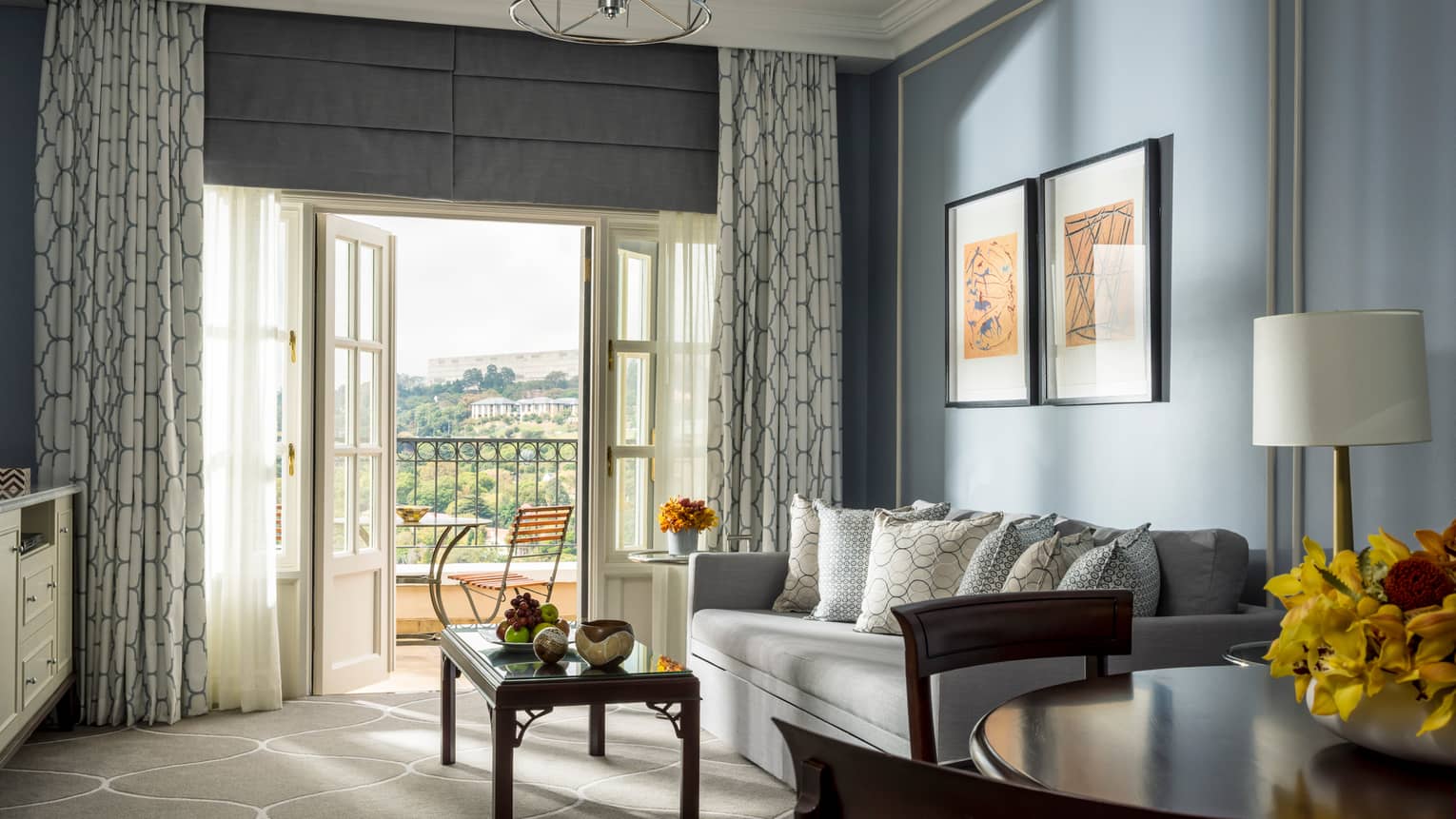 Panoramic-View One-Bedroom Suite round dining table, sofa and coffee table near open French doors to sunny balcony