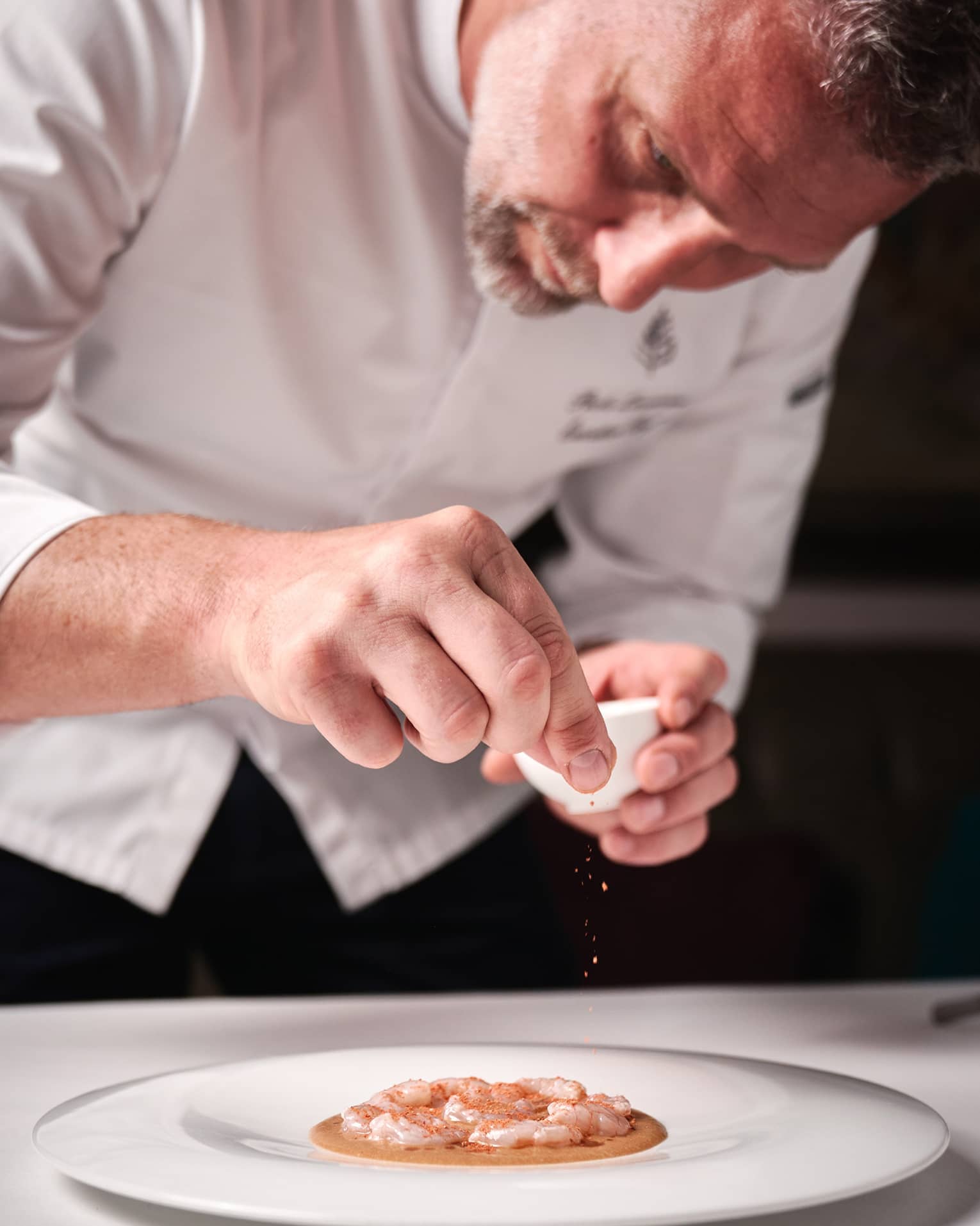 Four Seasons chef garnishing a seafood dish on a white plate