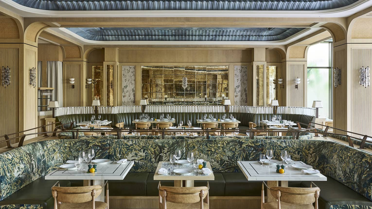 Bright, open restaurant space with neutral-coloured walls, decorative recessed ceilings, natural light, and tables and chairs and banquette seating