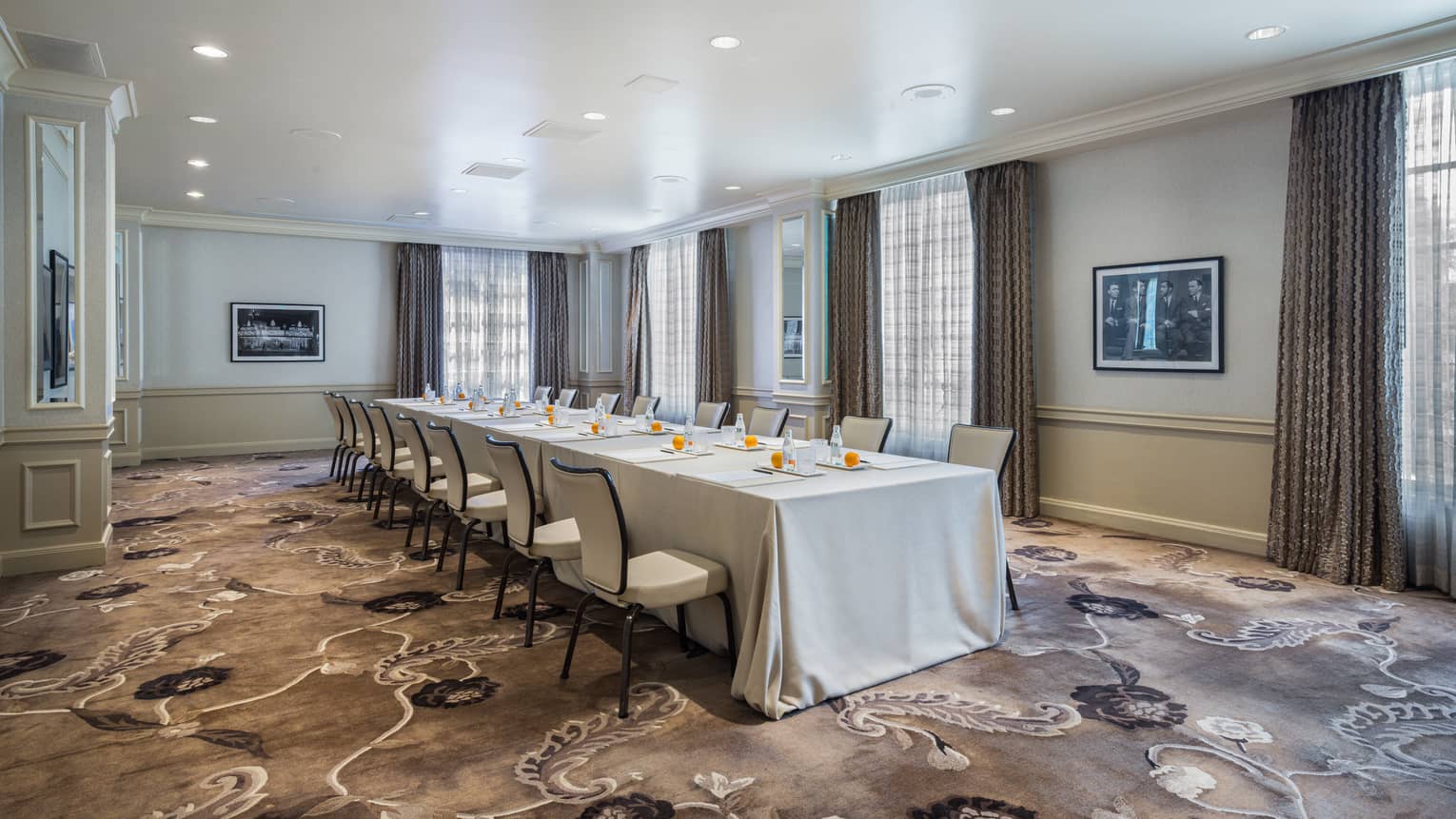 Meeting room set up boardroom style with floor-to-ceiling windows, ambient lighting and dark patterned carpet