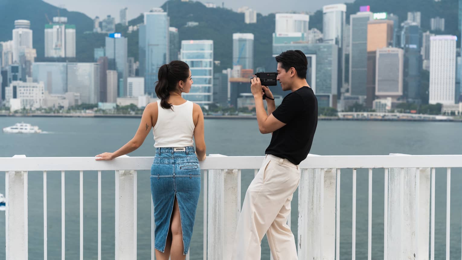 Man takes a photo of a woman near Victoria Harbour in Hong Kong