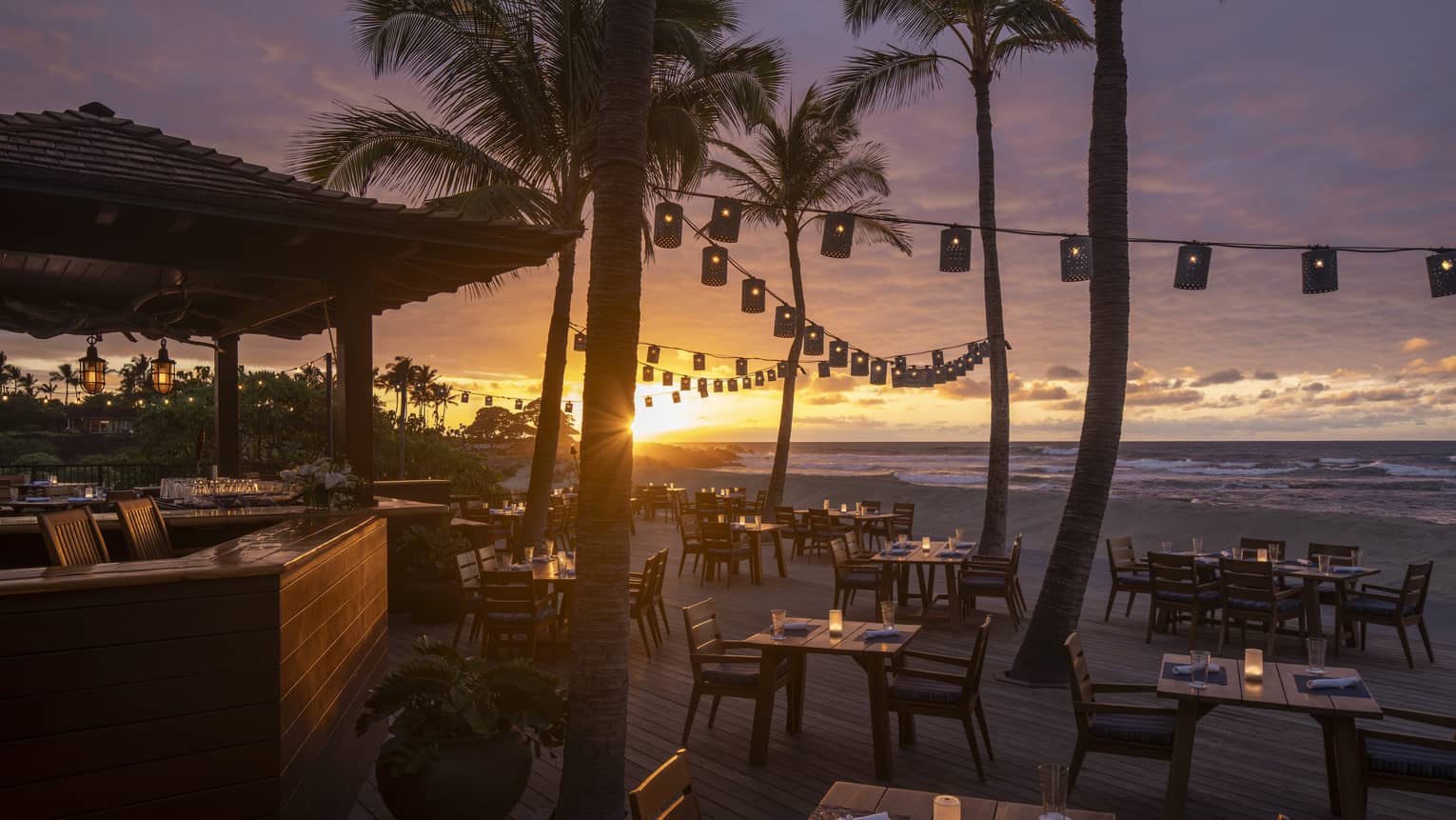 Beachfront outdoor restaurant terrace with string lights at sunset