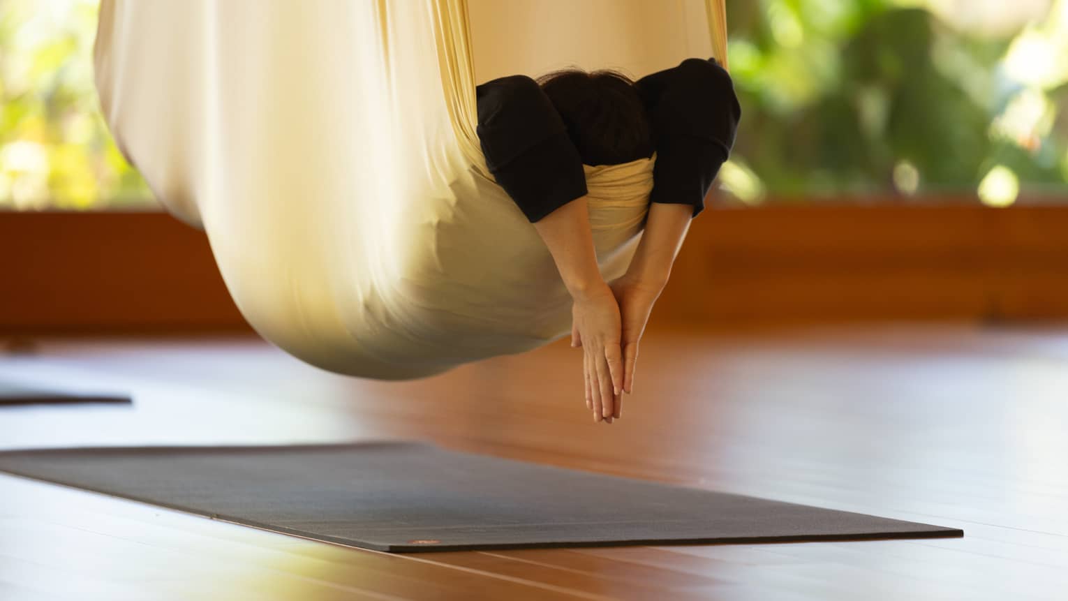 A person practicing hanging yoga.