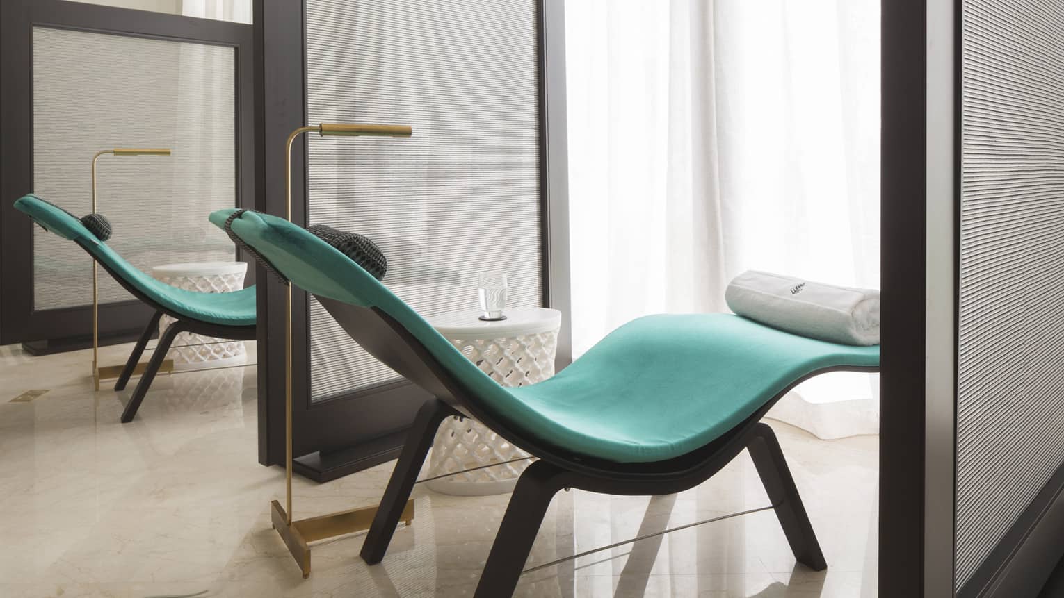 Two curved aqua spa chairs separated by privacy screens
