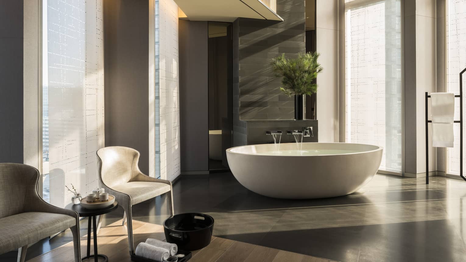 Water pouring into round white bath, two chairs, towels and foot bath at Sulwhasoo spa