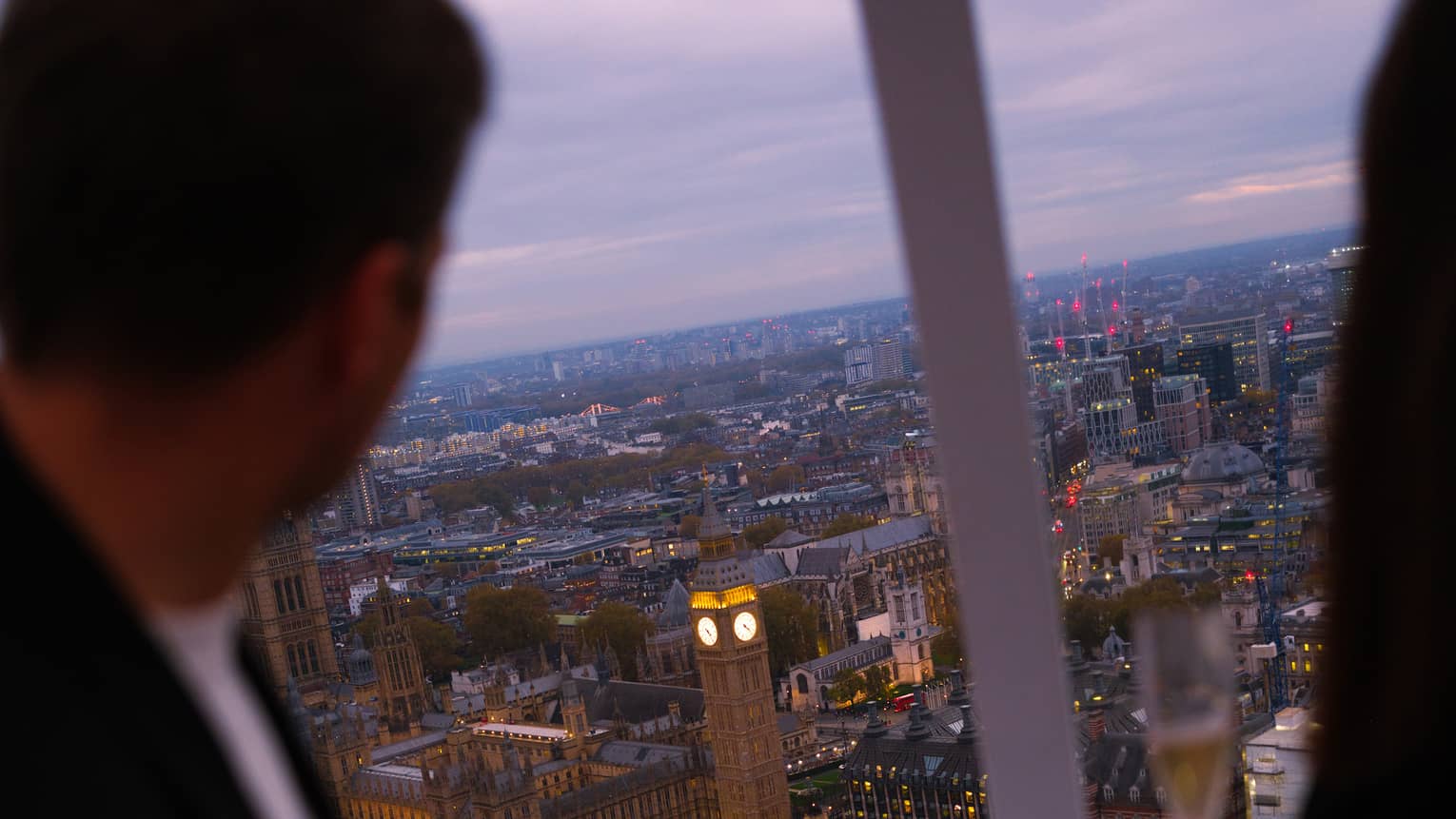 People look out over a city from above from a capsule on a large ferris wheel.