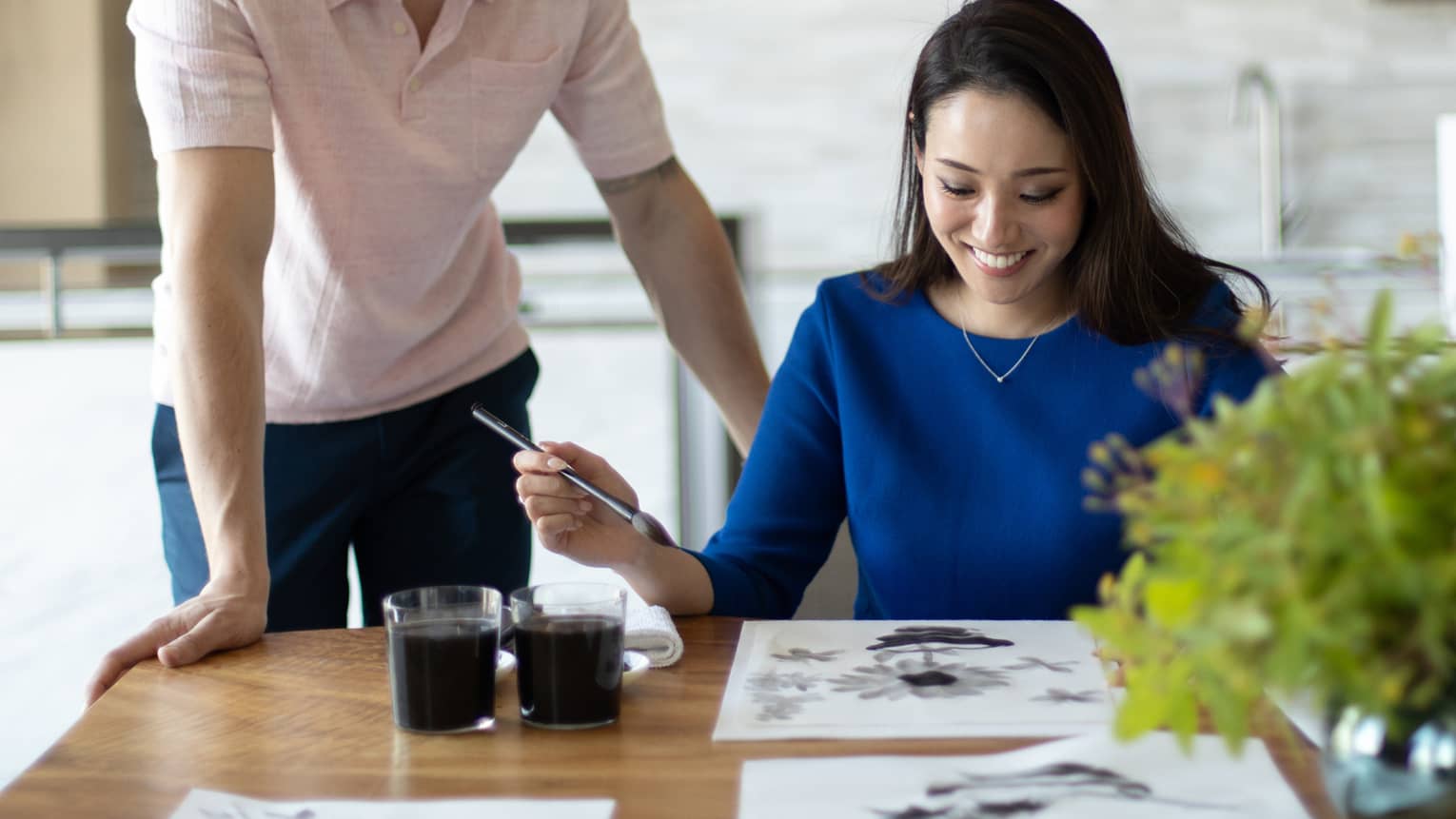 Person smiling while painting with watercolours at a table