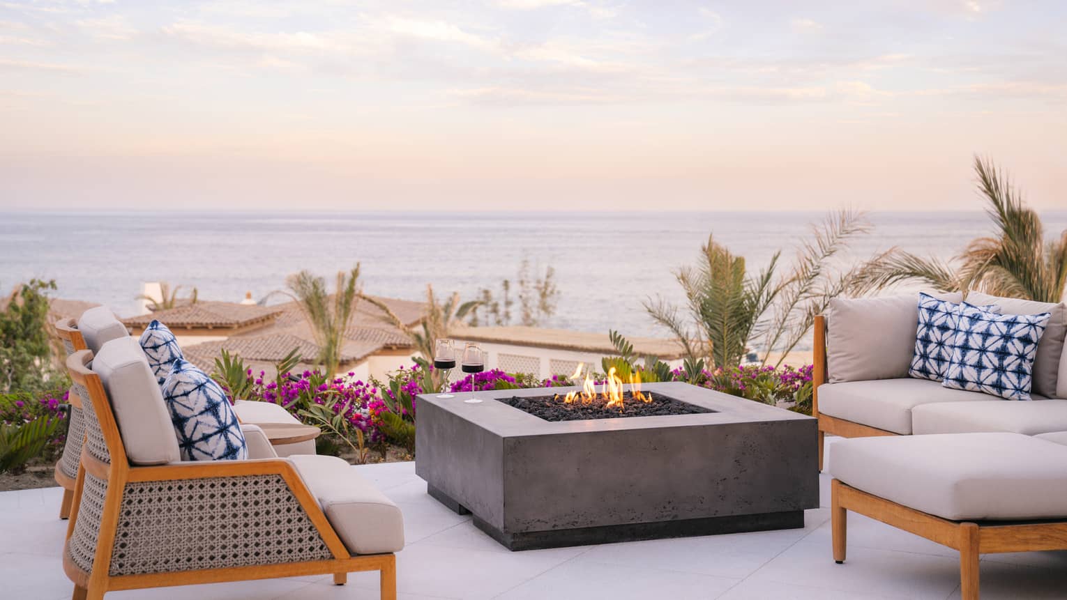 Outdoor lounge chairs and has firepit table and ocean view at luxury resort