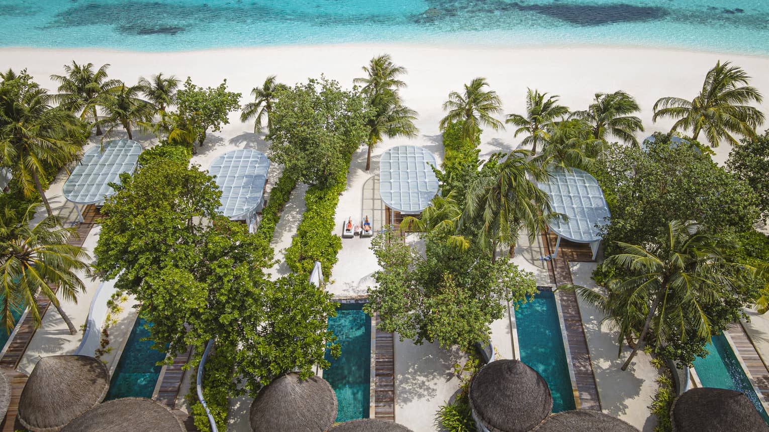 Aerial view of beachfront villas with pools at luxury tropical resort