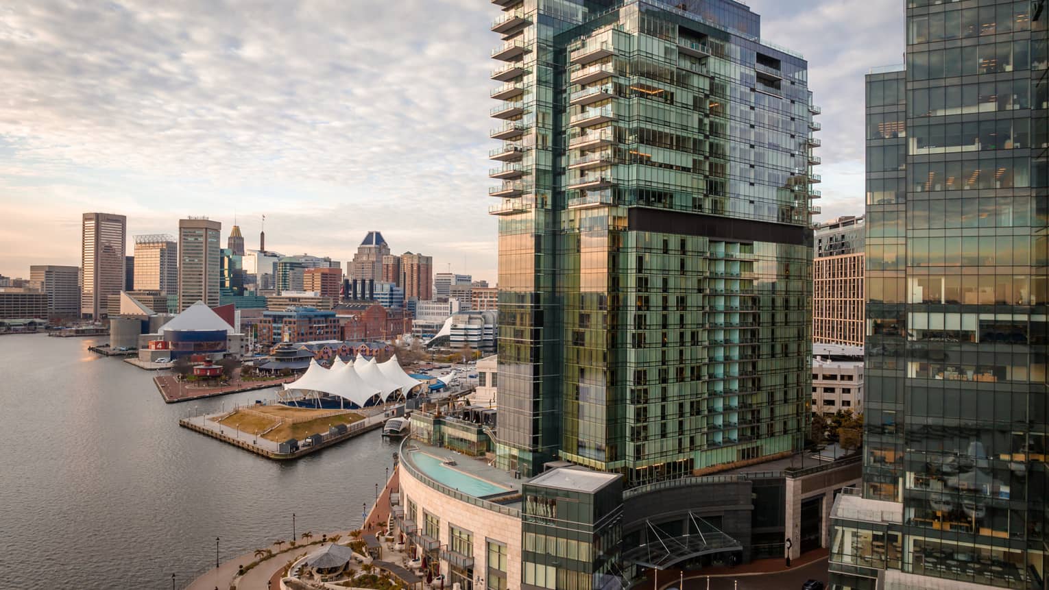Tall city buildings near a harbour with clouds in the sky above