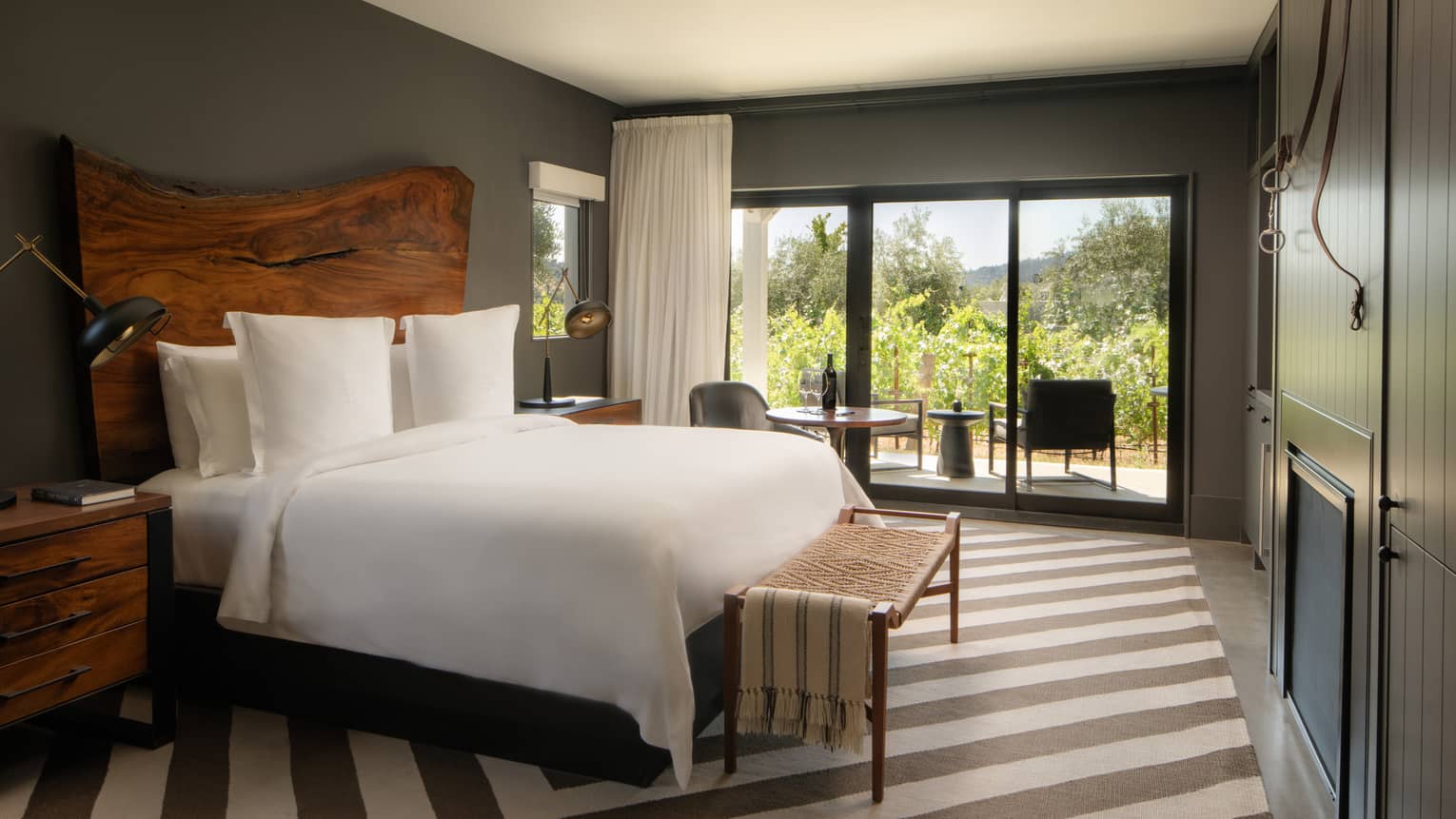 Contemporary room at a resort, featuring king bed with natural-wood headboard, striped rug and walk-out terrace