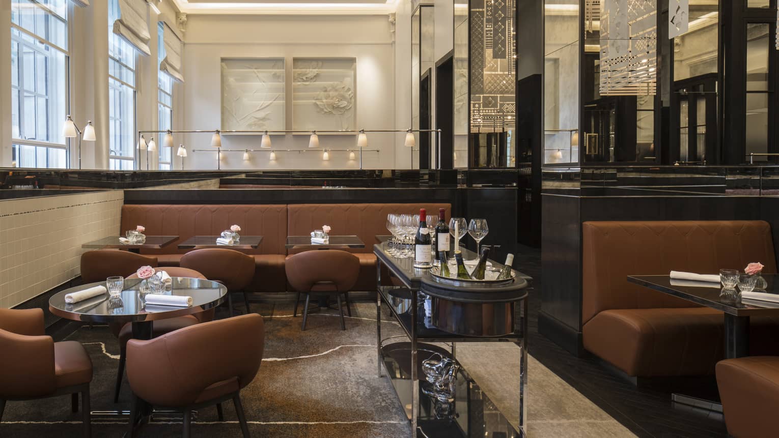 A dining area with brown chairs and booths and black tables.