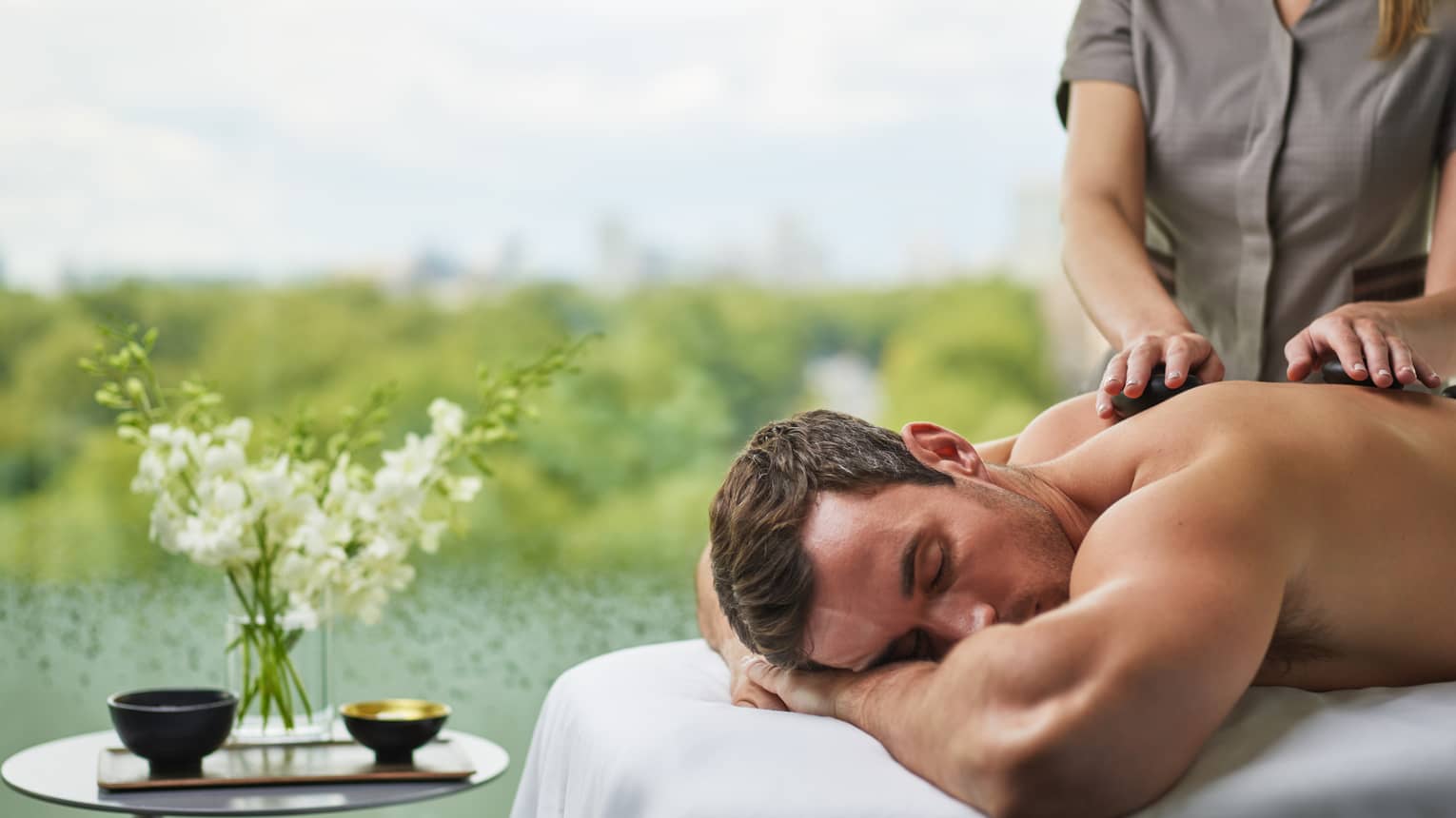 A man receives a massage next to a pond.