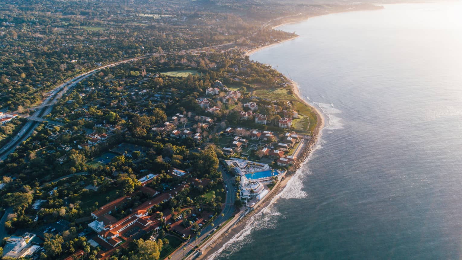 Aerial view of Santa Barbara coastline, trees and winding highways at sunset