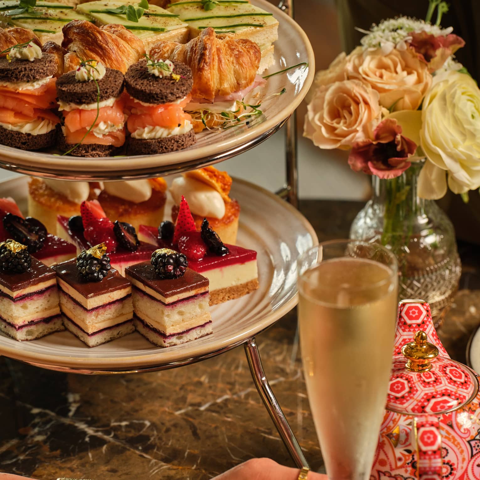 A three-tiered display of sweets beside a vase of flowers