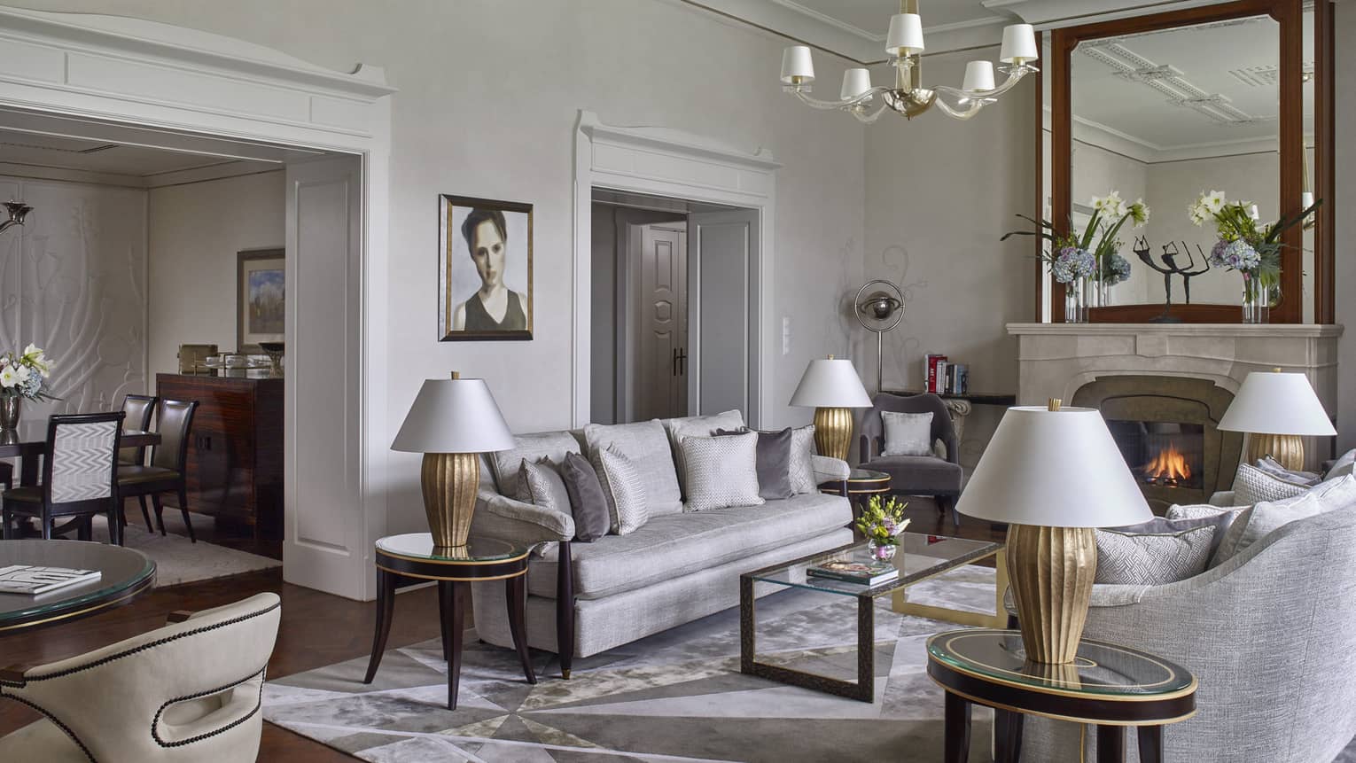 Elegant hotel living room with gray sofas, modern lamps and a fireplace with a large mirror above