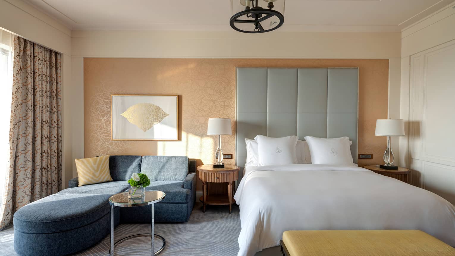 Bedroom with queen bed, tall grey headboard, dark blue sofa