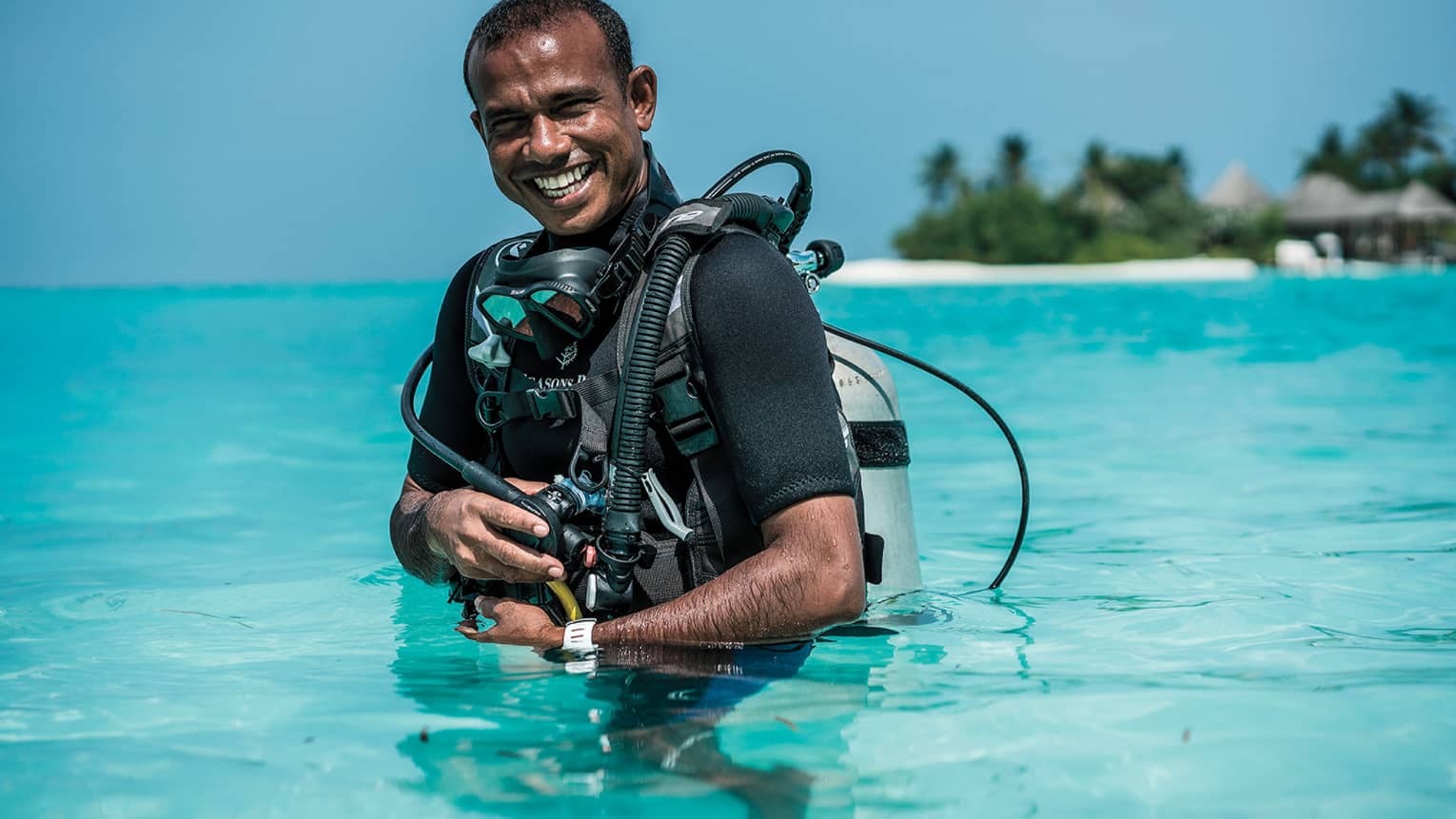 Smiling Dive Manager Ibrahim Nazeer with scuba gear in the crystal clear waters of the lagoon
