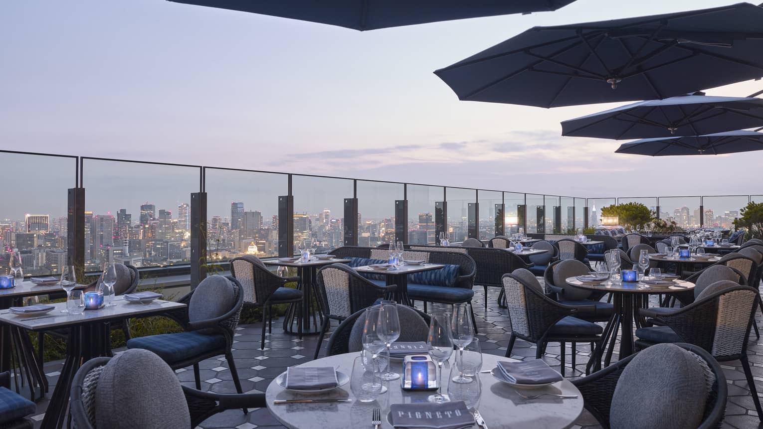 Pigneto Terraza rooftop patio dining tables at dusk, city view below