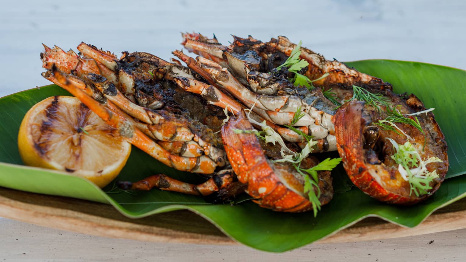 Grilled king prawns with grilled lemon half atop banana leaf