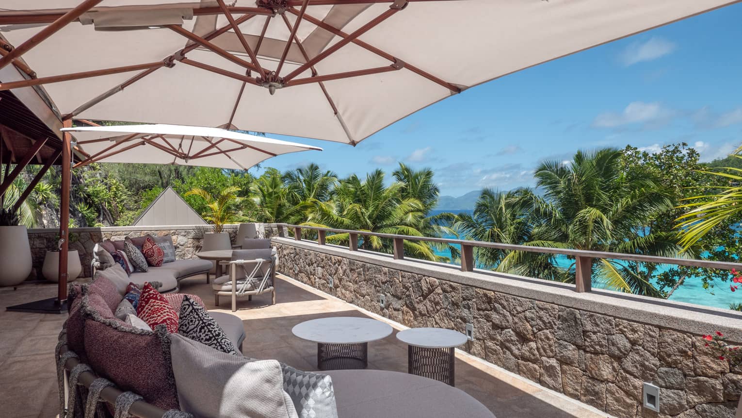 Outdoor lounge seating set under umbrellas on tropical sea-view terrace