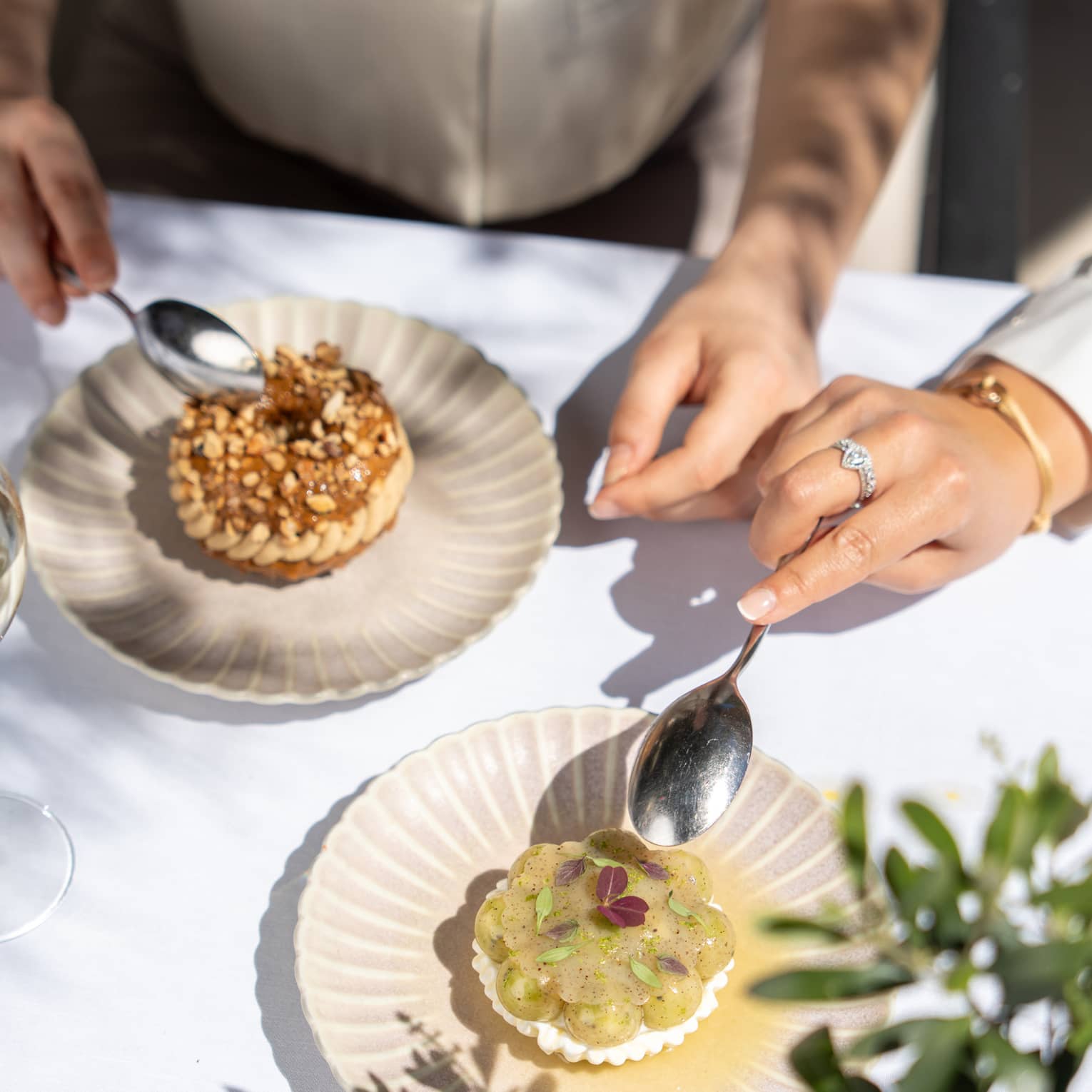 Two people partake of elegant desserts on artistic scallop-edged plates.