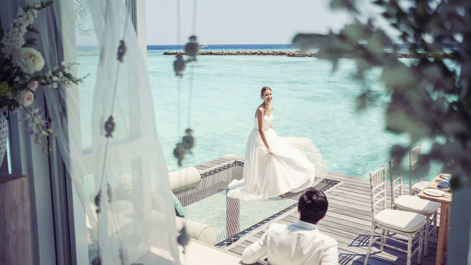 Bride and groom relax before their reception in their overwater wedding bungalow with glass-bottom floor