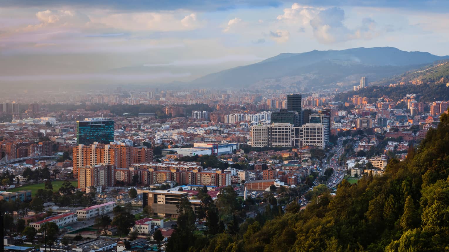 Aerial view of Bogota city, buildings and houses below misty mountains