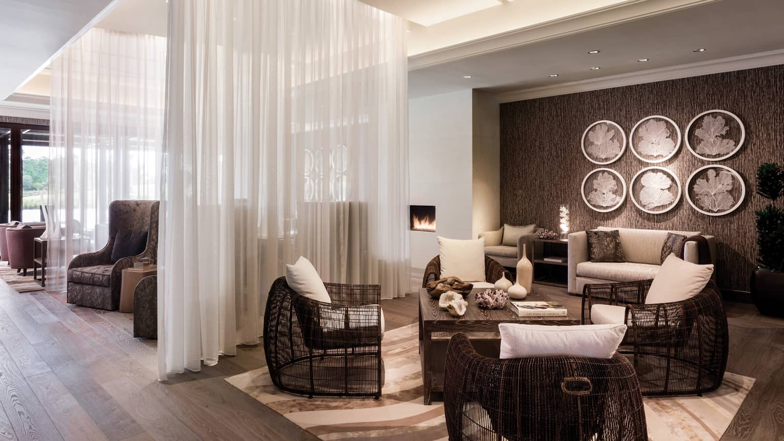 Spa lounge, wicker armchairs with white cushions, room divided by sheer white curtains