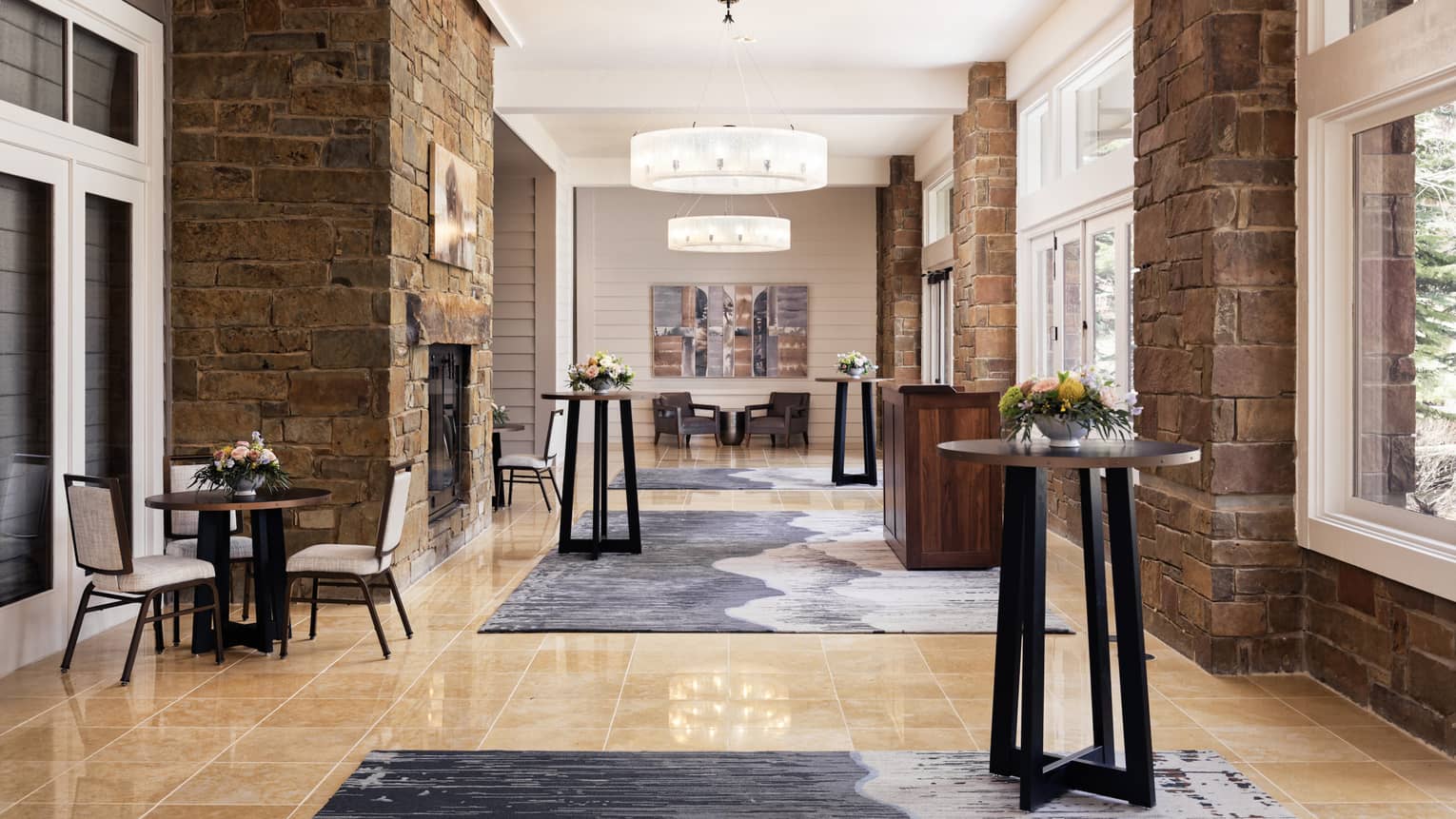 A reception area with standing tables, small tables with chairs and large windows.