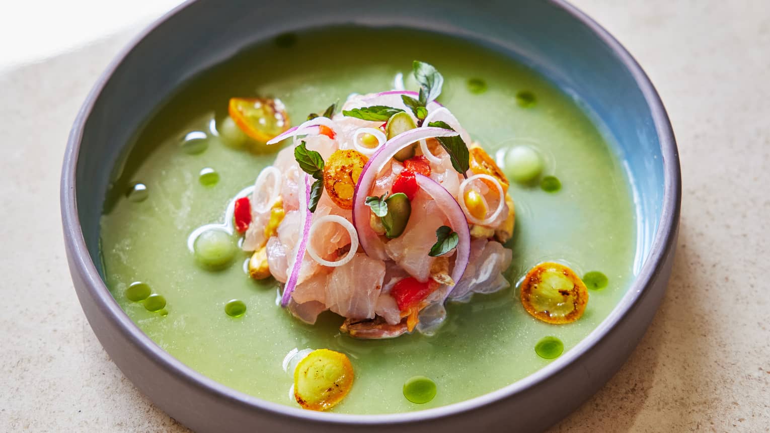 Food in a green sauce in a grey bowl.