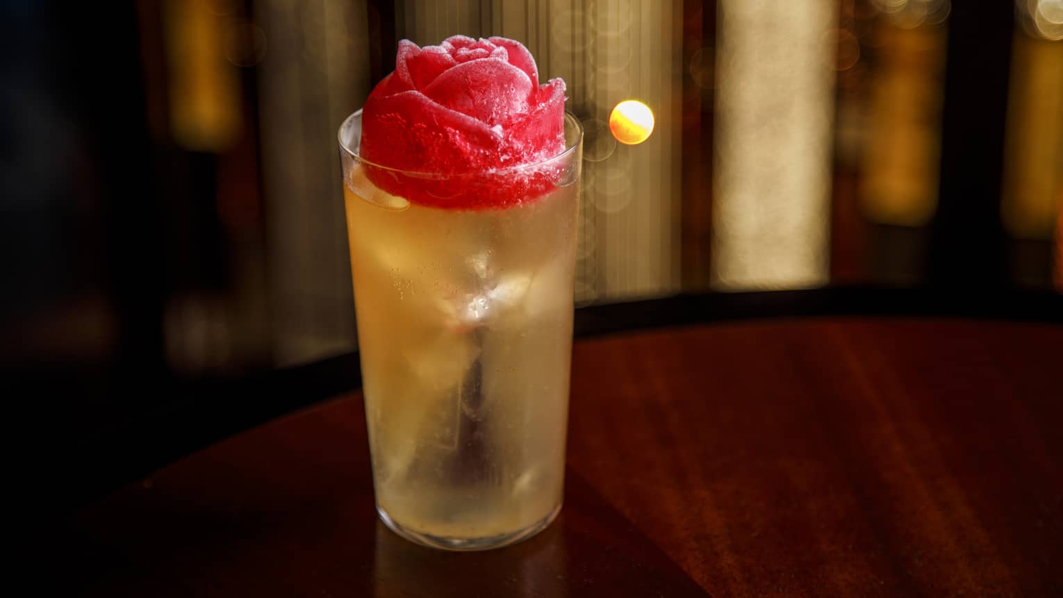 Yellow-hued cocktail in tall glass with rose-shaped ice cube
