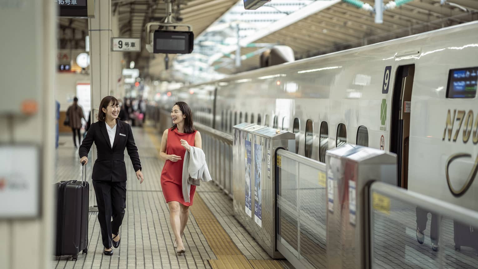 Train station greeter walks with female guest along the train platform
