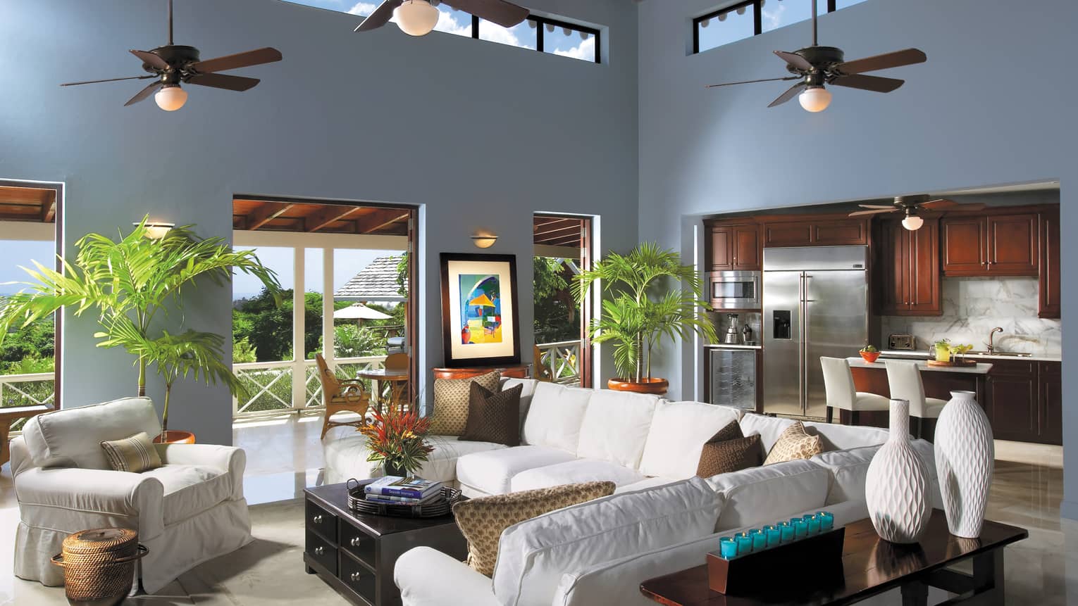 Plush white sofas by wood table, modern white vases, kitchen in background