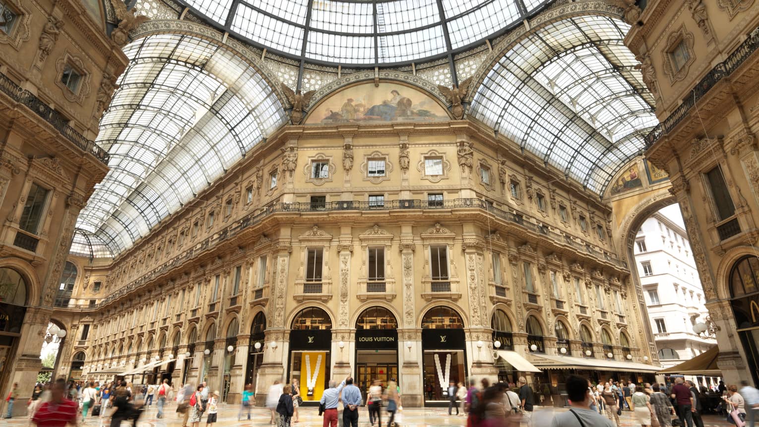 Shoppers gathered in historic Galleria Vittorio Emanuele building with soaring ceilings, shops
