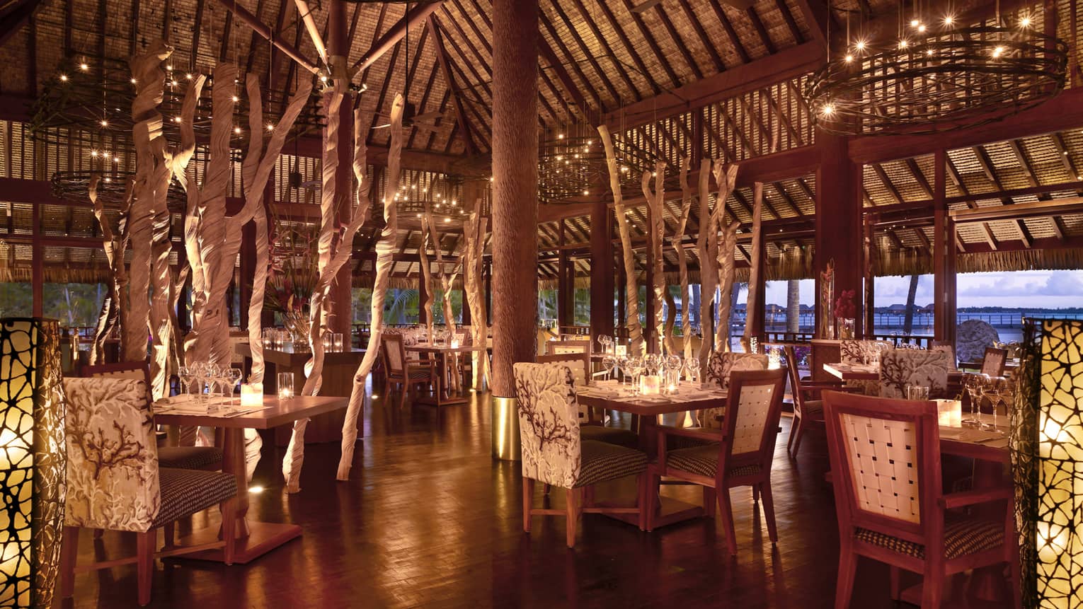 Elegant, candle-lit Arii Moana open-air dining room with plush chairs, decorative branches