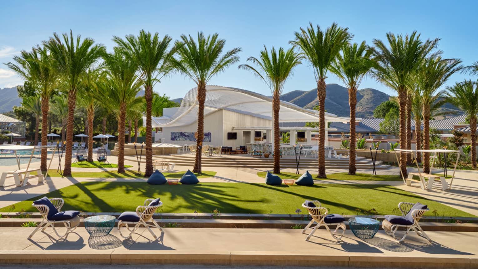 An outdoor sitting area with grass and palm trees.