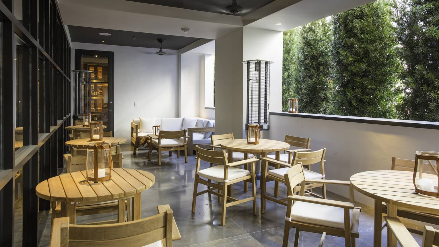 A patio eating area with small wooden tables and wood seats.