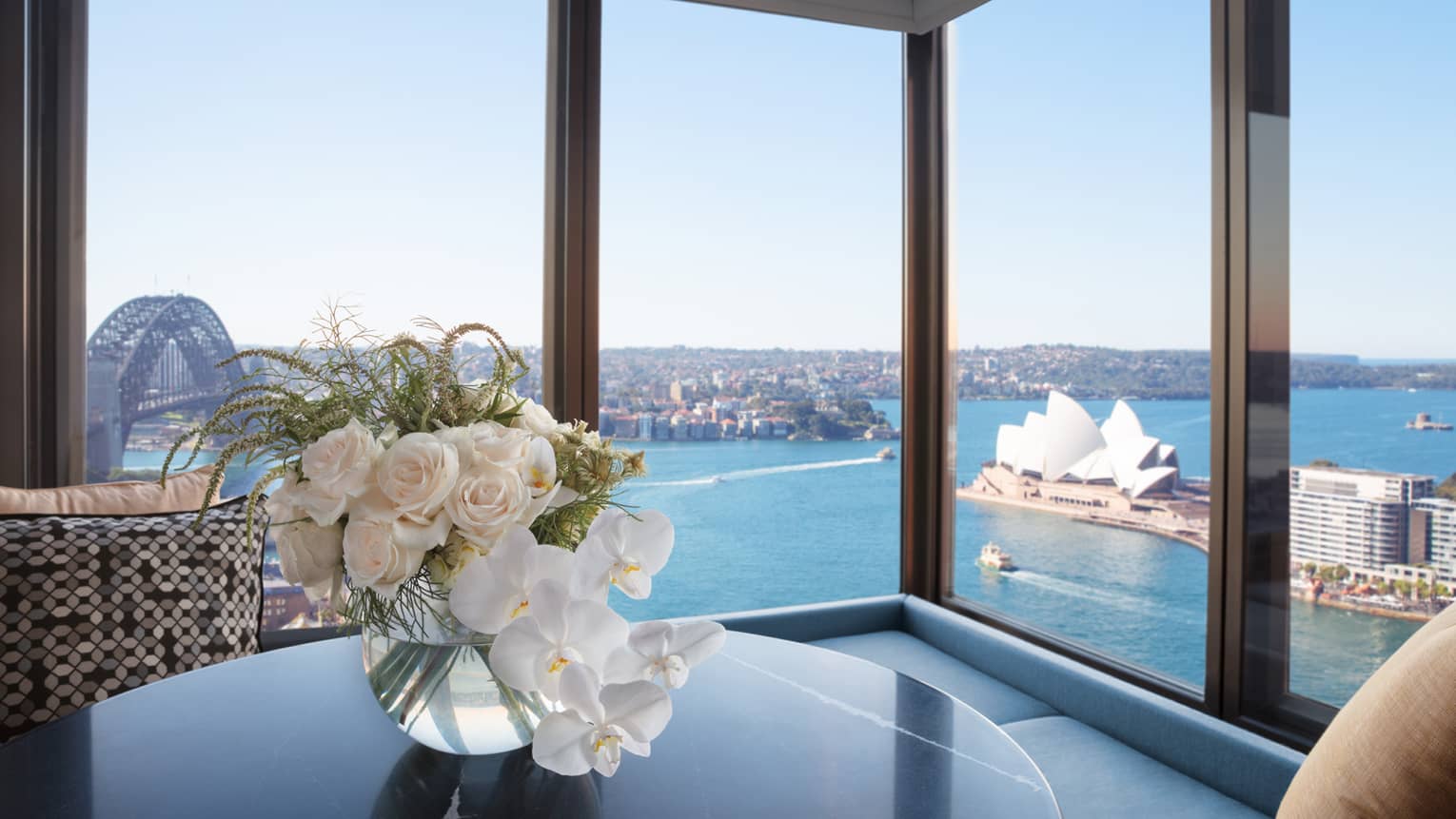 White roses on table by corner floor to ceiling windows overlooking Sydney Harbour